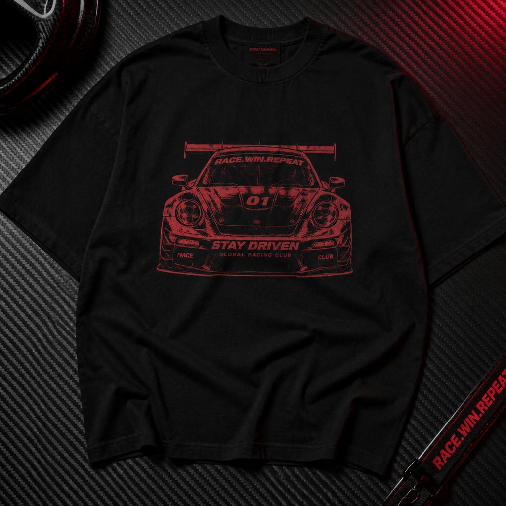 Black car-graphic tee laid flat on carbon fibre under red light